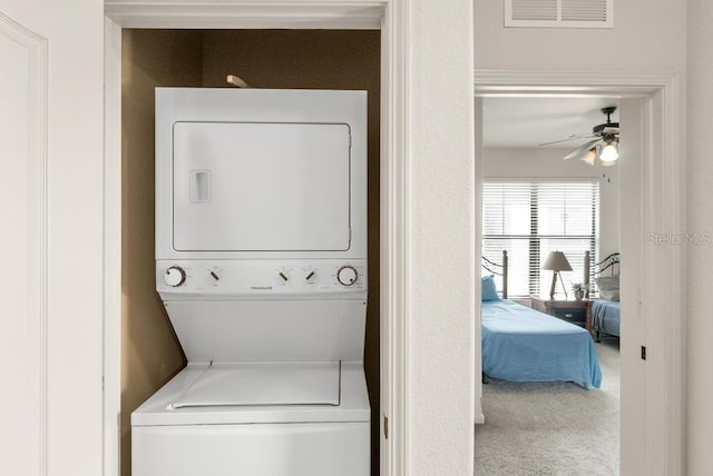 washroom with ceiling fan, carpet flooring, and stacked washer and dryer