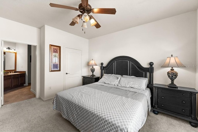 bedroom with ceiling fan, ensuite bath, sink, and light colored carpet