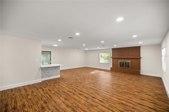 unfurnished living room featuring dark hardwood / wood-style flooring and a brick fireplace