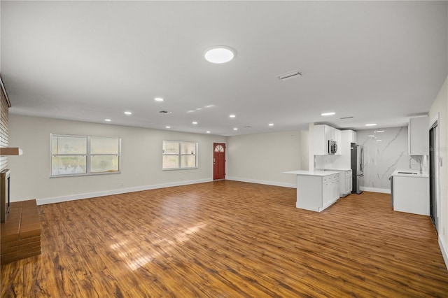 unfurnished living room featuring hardwood / wood-style flooring, a brick fireplace, and sink