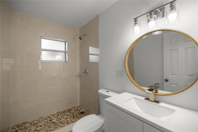 bathroom featuring tiled shower, vanity, and toilet