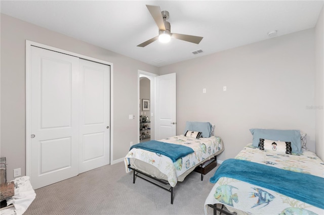 bedroom with ceiling fan, a closet, and light colored carpet