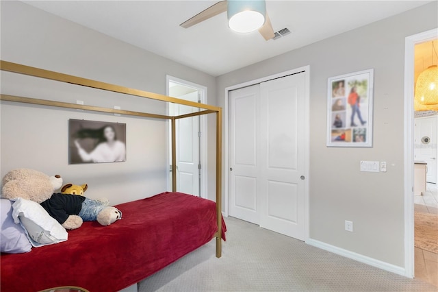 bedroom with ceiling fan, light colored carpet, and a closet