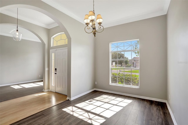 foyer with an inviting chandelier, dark hardwood / wood-style floors, and ornamental molding