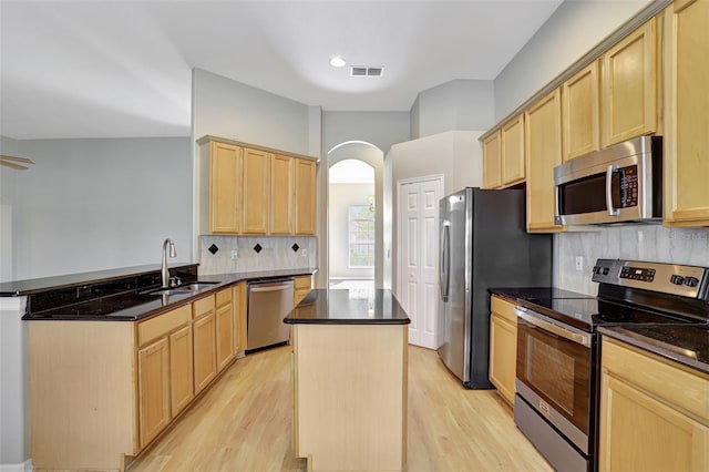 kitchen featuring kitchen peninsula, stainless steel appliances, light hardwood / wood-style floors, and sink