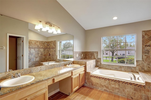 bathroom featuring vanity, wood-type flooring, plus walk in shower, and vaulted ceiling