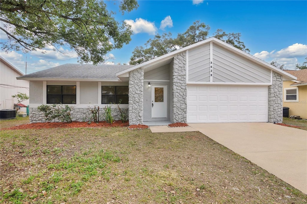 single story home featuring a front lawn, cooling unit, and a garage