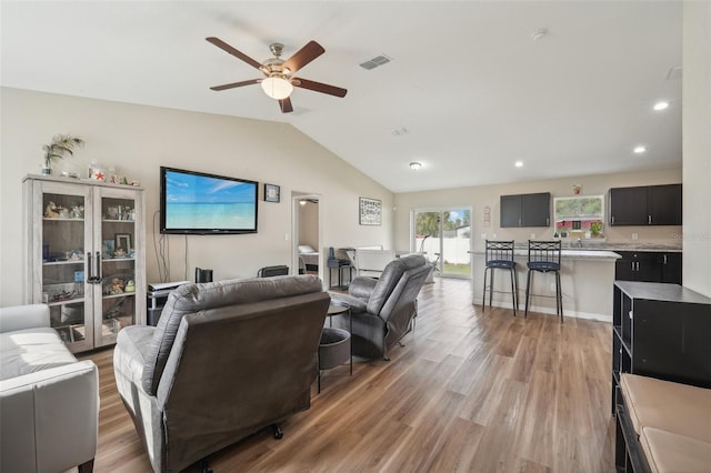 living room featuring light hardwood / wood-style floors, vaulted ceiling, and ceiling fan