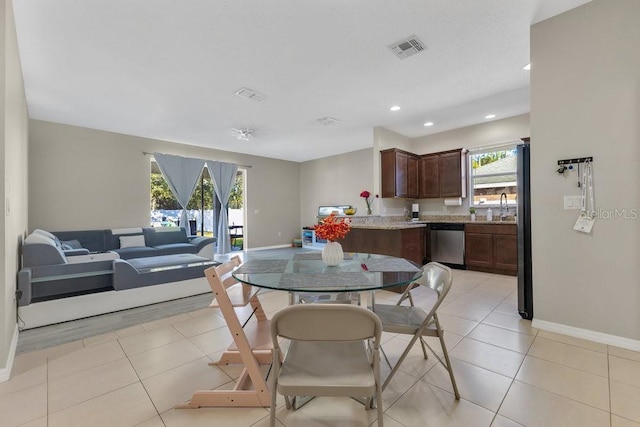 dining room featuring a healthy amount of sunlight, sink, and light tile patterned floors