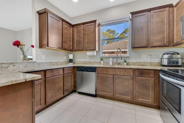 kitchen with stainless steel appliances, light stone countertops, sink, and light tile patterned floors