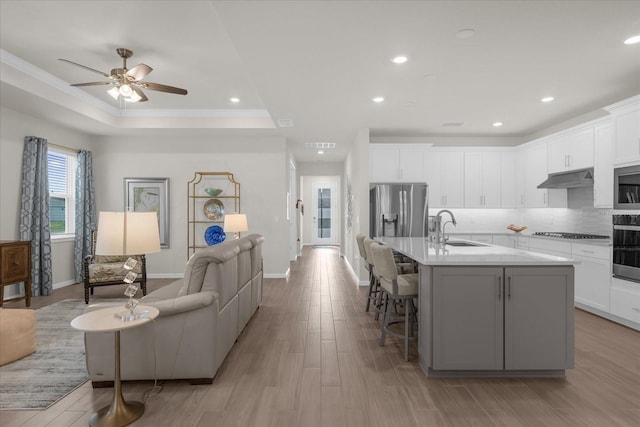 kitchen featuring sink, an island with sink, appliances with stainless steel finishes, a kitchen bar, and white cabinetry