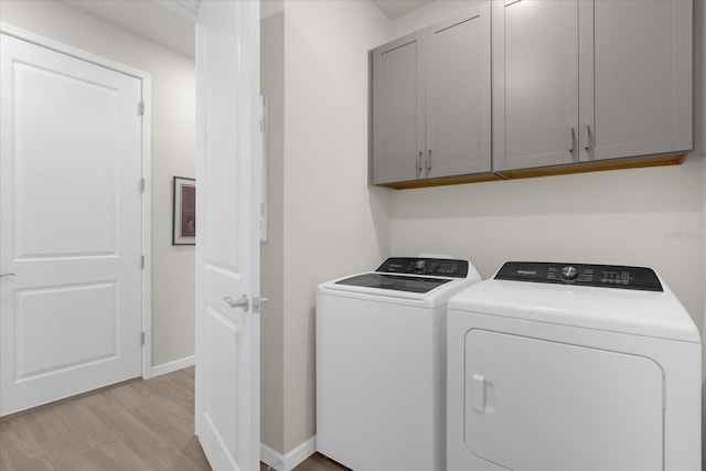 laundry area featuring cabinets, washer and dryer, and light wood-type flooring