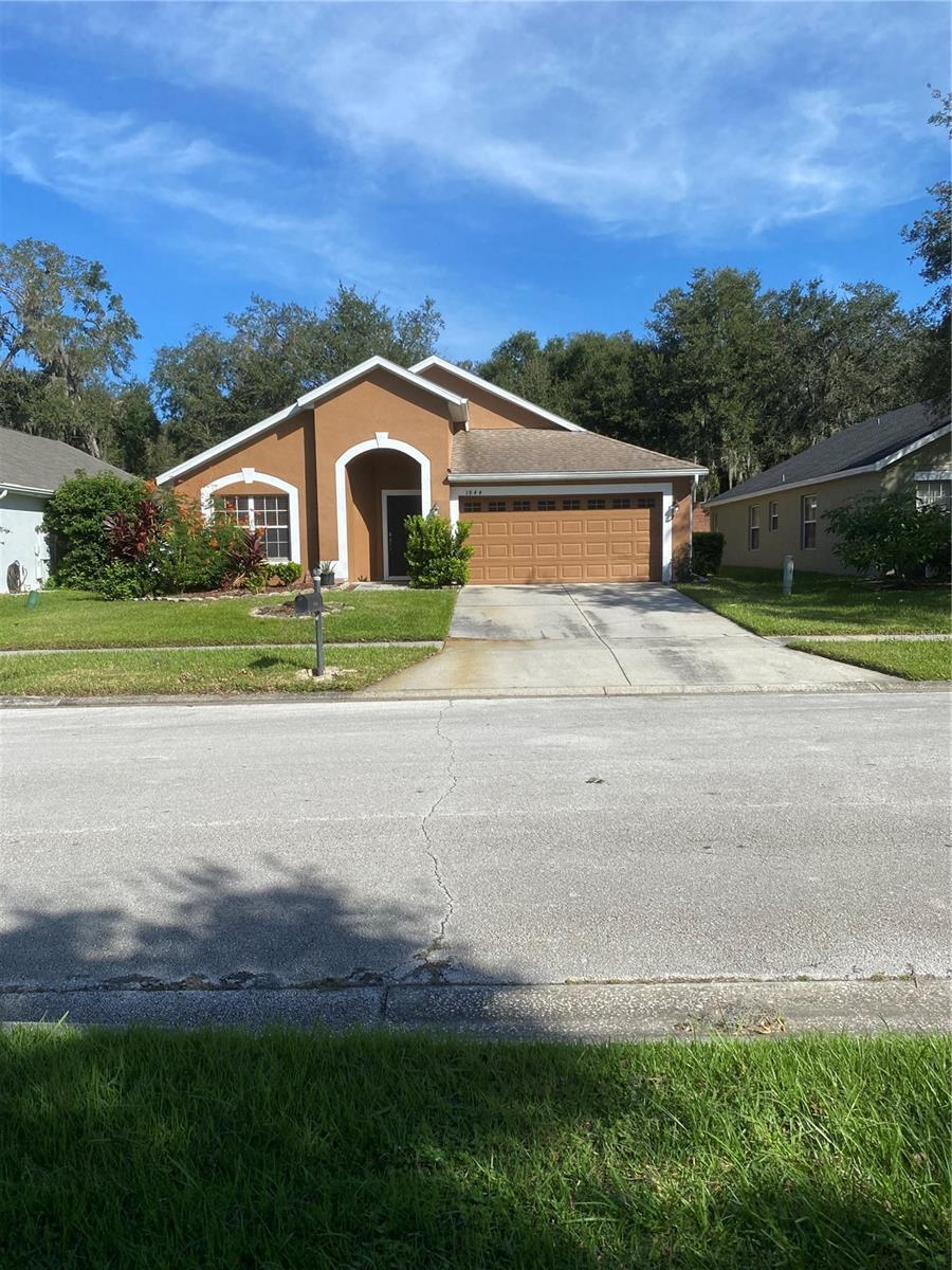 single story home with driveway, stucco siding, a garage, and a front yard