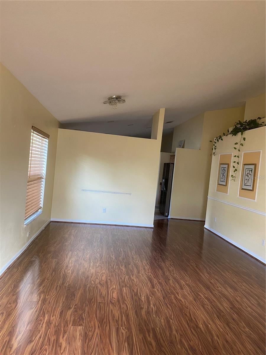 unfurnished living room with wood finished floors, lofted ceiling, and baseboards