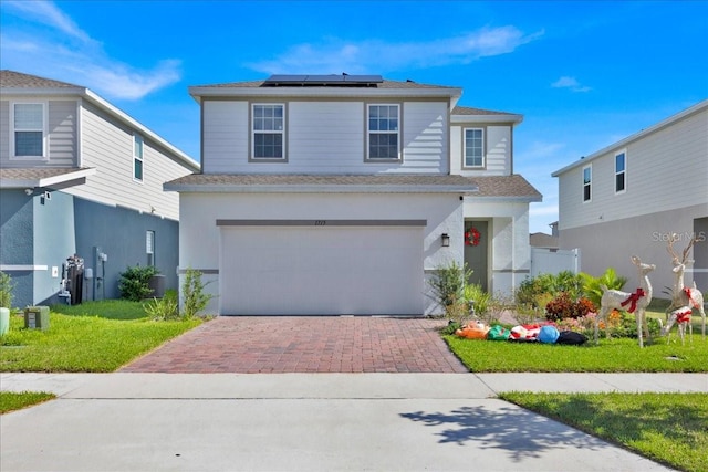 view of front property featuring solar panels, a garage, and a front lawn