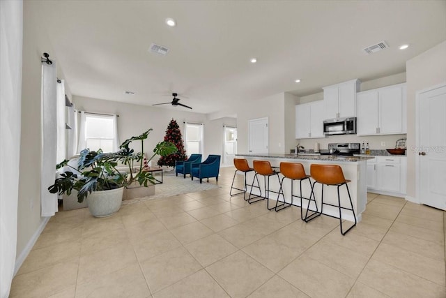 kitchen featuring a healthy amount of sunlight, white cabinetry, stainless steel appliances, and a kitchen island with sink