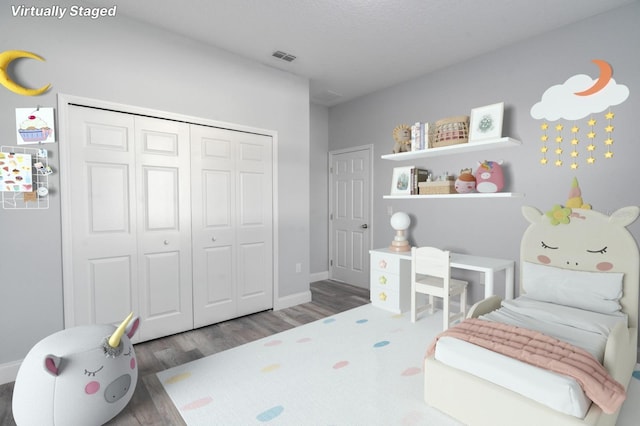 bedroom with a closet, a textured ceiling, and dark hardwood / wood-style floors