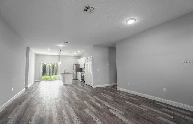 unfurnished living room with sink, dark hardwood / wood-style floors, and a textured ceiling