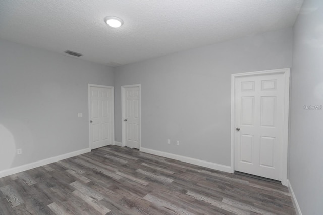 spare room featuring dark wood-type flooring and a textured ceiling