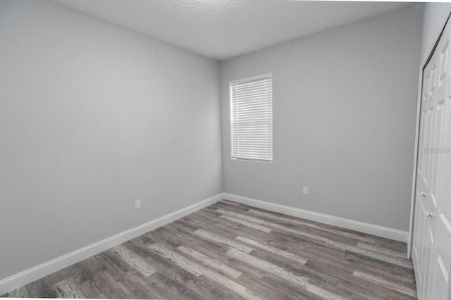 empty room with light wood-type flooring and a textured ceiling