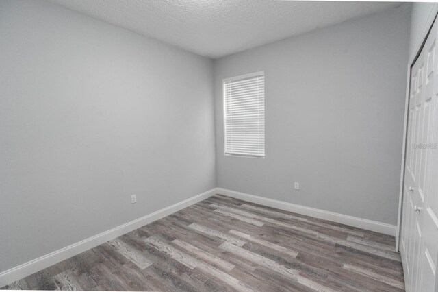 13869 SW 114th Pl, Dunnellon, FL 34432 - unfurnished bedroom featuring wood finished floors, a closet, baseboards, and a textured ceiling