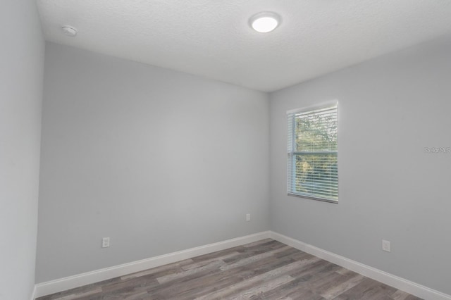 empty room featuring a textured ceiling and light hardwood / wood-style flooring