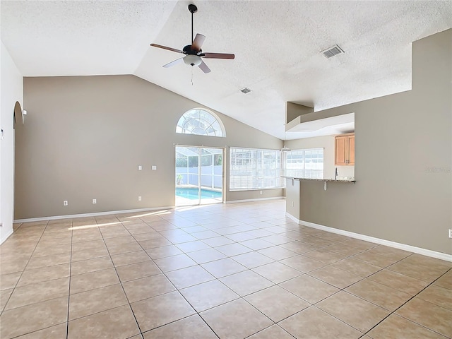 unfurnished room featuring ceiling fan, light tile patterned floors, lofted ceiling, and a textured ceiling