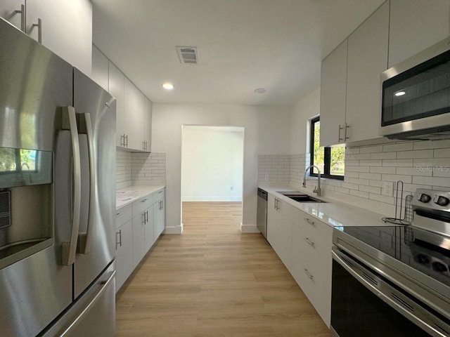 kitchen featuring white cabinetry, light wood-type flooring, stainless steel appliances, and sink