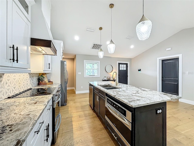 kitchen with white cabinets, stainless steel appliances, a kitchen island with sink, and sink