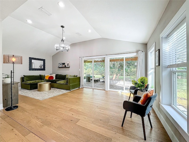 living room with an inviting chandelier, light hardwood / wood-style floors, and vaulted ceiling