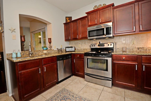 kitchen featuring appliances with stainless steel finishes, sink, backsplash, light stone countertops, and light tile patterned flooring