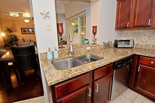 kitchen featuring kitchen peninsula, stainless steel dishwasher, sink, light tile patterned floors, and light stone counters