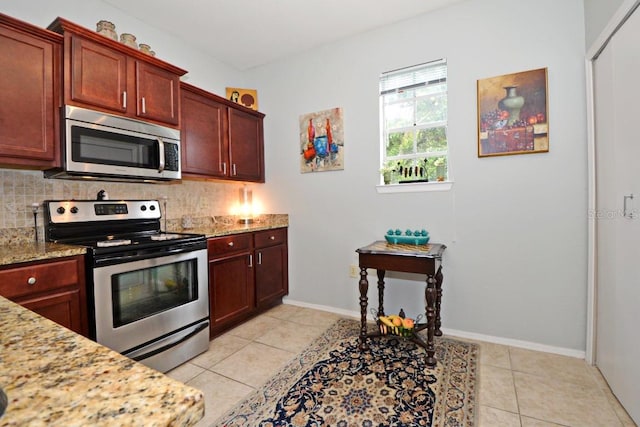 kitchen featuring light stone countertops, backsplash, light tile patterned floors, and appliances with stainless steel finishes