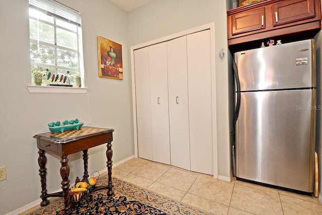 kitchen with light tile patterned floors and stainless steel fridge