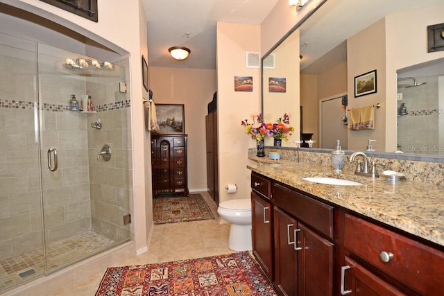 bathroom with a shower with shower door, toilet, vanity, and tile patterned flooring