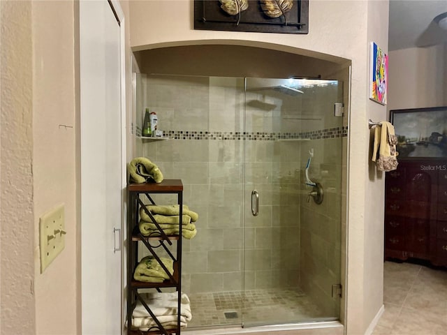 bathroom with a shower with door and tile patterned flooring