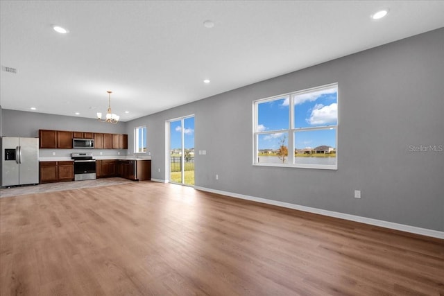 unfurnished living room with a chandelier and light hardwood / wood-style floors