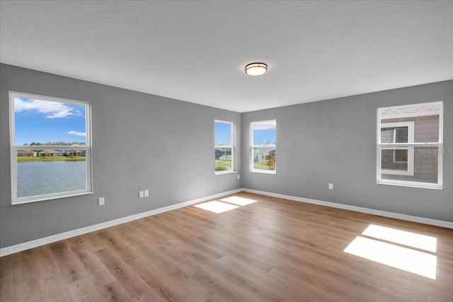 empty room featuring a water view and light hardwood / wood-style flooring