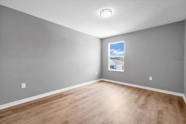 empty room featuring a textured ceiling and light wood-type flooring