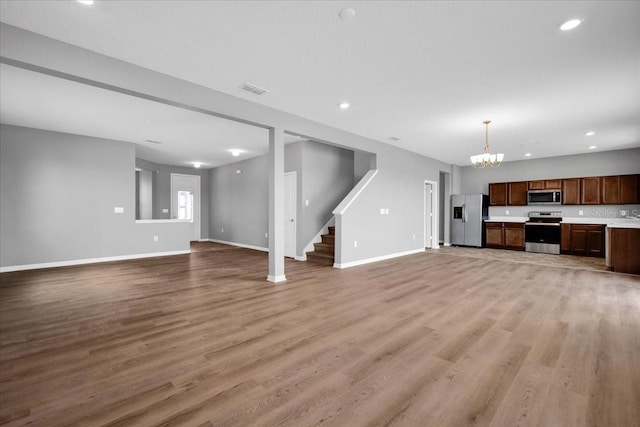 unfurnished living room featuring light hardwood / wood-style flooring and an inviting chandelier