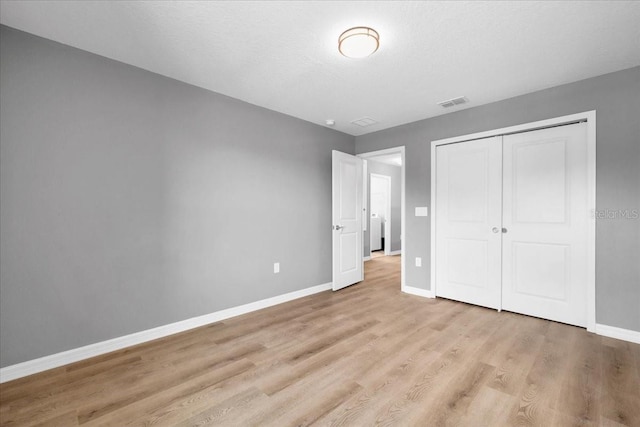 unfurnished bedroom featuring a textured ceiling, light hardwood / wood-style flooring, and a closet