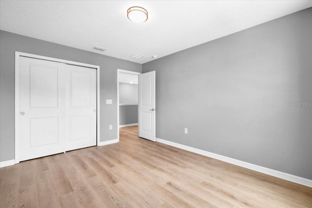 unfurnished bedroom with light hardwood / wood-style flooring and a closet