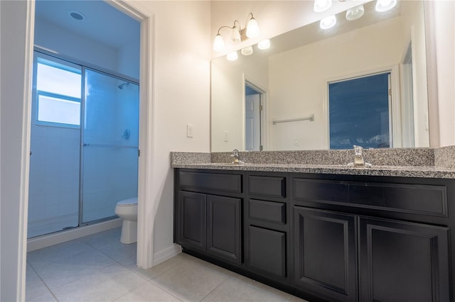 bathroom with tile patterned flooring, vanity, a shower with door, and toilet