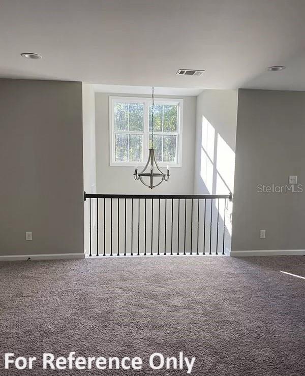 empty room with carpet flooring and an inviting chandelier