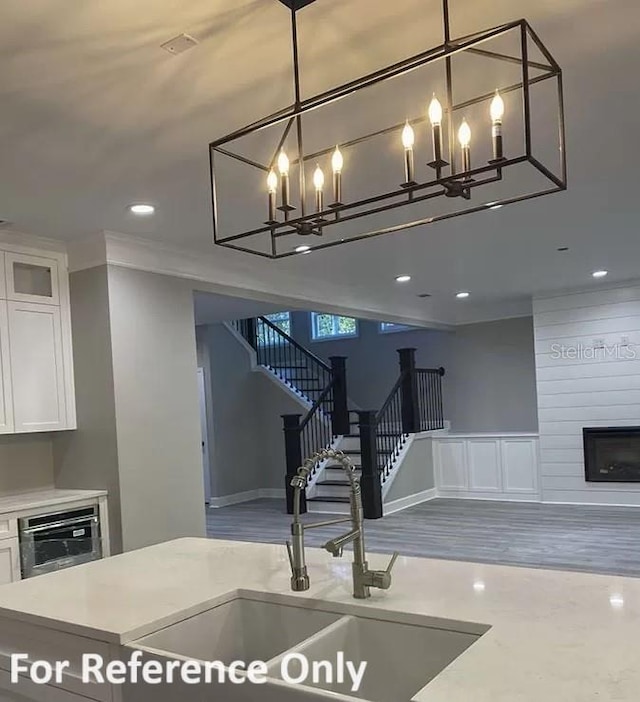 interior space featuring a large fireplace, sink, oven, decorative light fixtures, and white cabinets