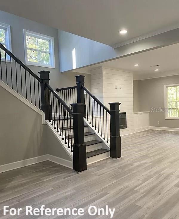 staircase with ornamental molding, a healthy amount of sunlight, and wood-type flooring