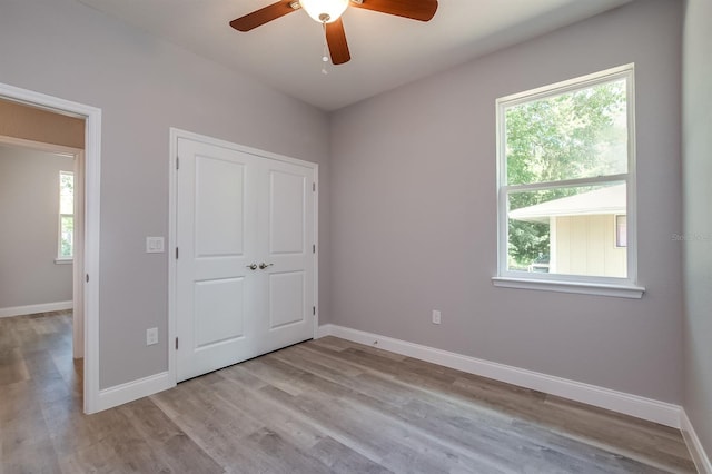 unfurnished bedroom featuring light wood-type flooring, a closet, ceiling fan, and baseboards