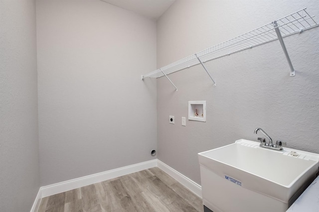 clothes washing area featuring laundry area, hookup for an electric dryer, light wood-type flooring, washer hookup, and a sink