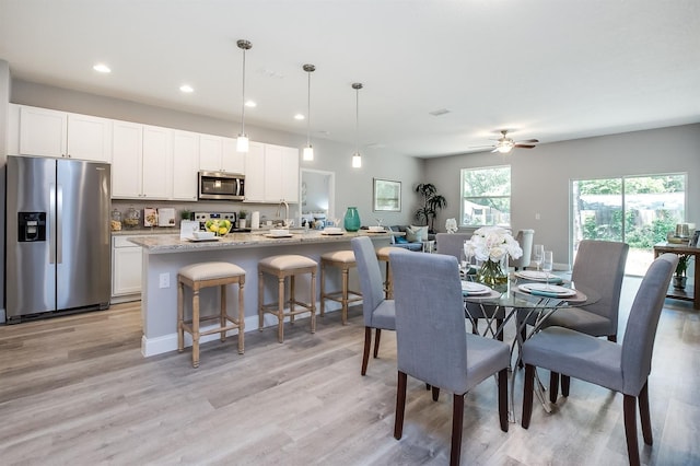 dining space featuring baseboards, light wood-type flooring, and recessed lighting