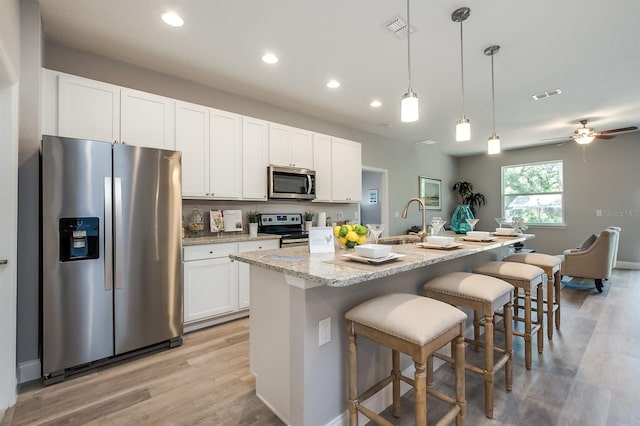 kitchen with an island with sink, white cabinetry, visible vents, and appliances with stainless steel finishes